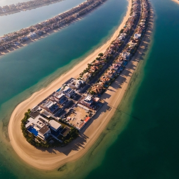 The Palm Jumeirah shaped island in Dubai United Arab Emirates aerial view at sunrise. Famous man made palm shaped island with luxury waterfront villas and hotels surrounded by seaside
